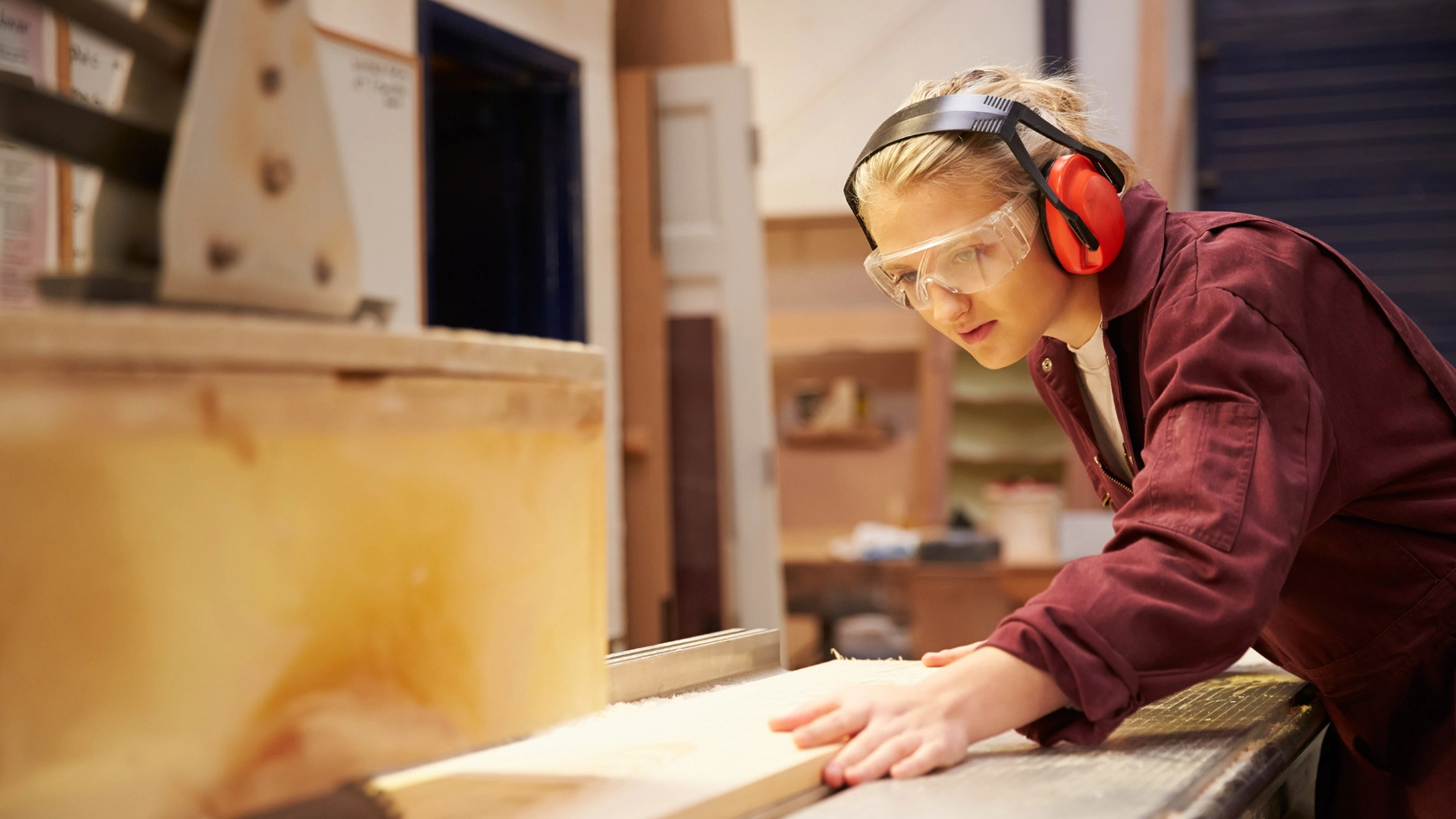 Auszubildende sägt an einer Kreissäge ein Holzbrett zurecht.