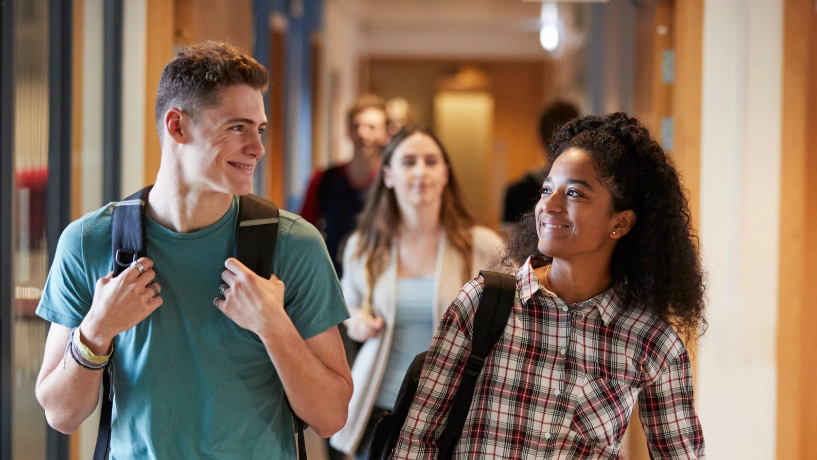 Eine Studentin und ein Student gehen gemeinsam über einen Korridor in einem Universitätsgebäude.