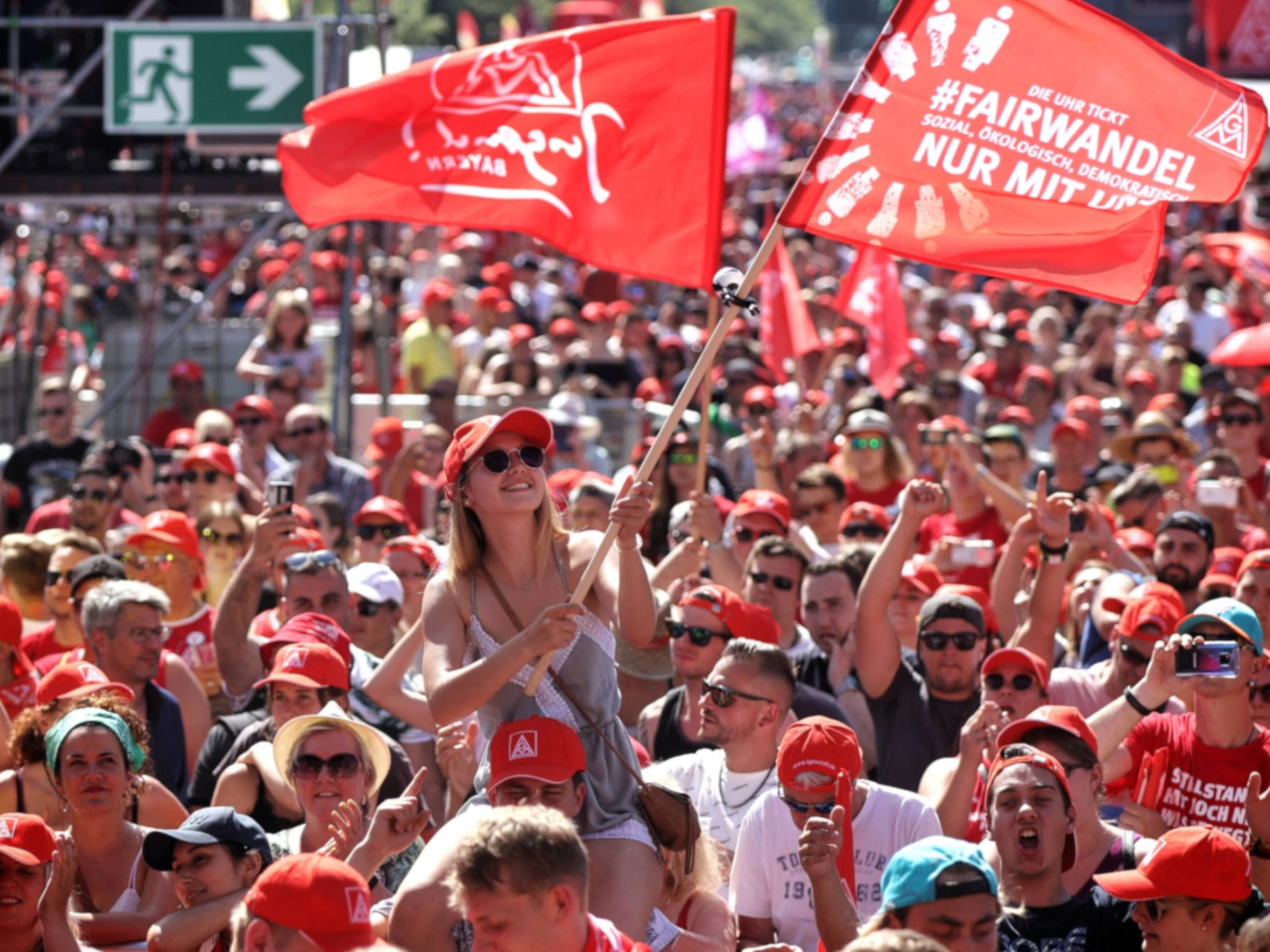 Eine junge Frau schwenkt eine Fahne auf der FairWandel-Kundgebung der IG Metall in Berlin.