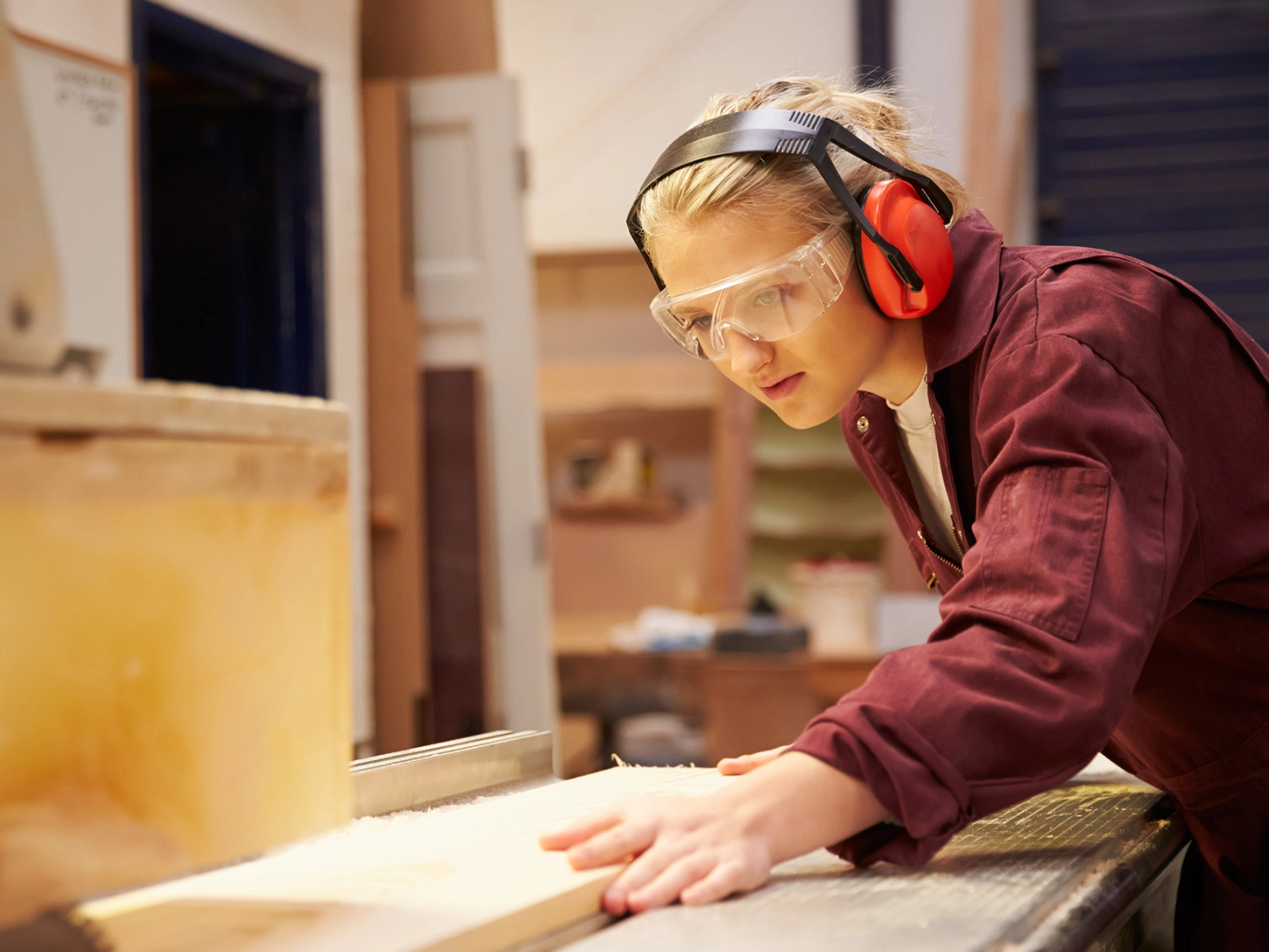 Auszubildende sägt an einer Kreissäge ein Holzbrett zurecht.