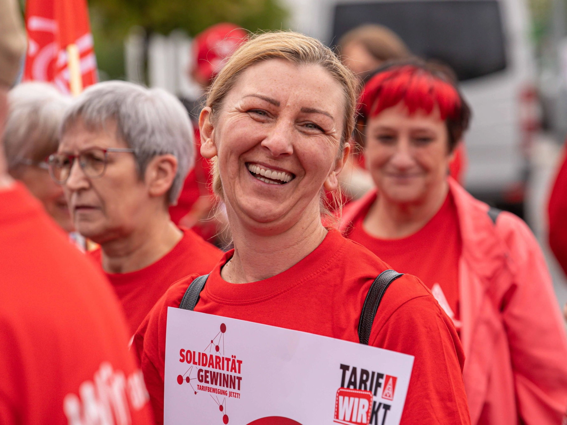 Eine Frau im roten T-Shirt lächelt in die Kamera.