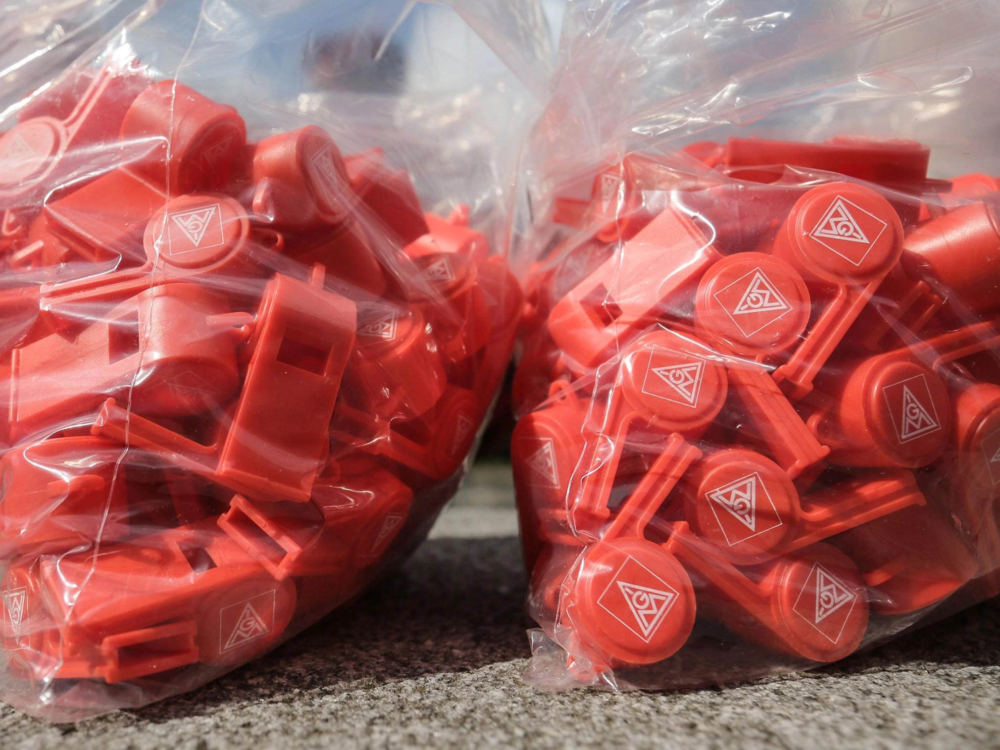 Rote IG Metall-Pfeifen in zwei Plastiktüten.